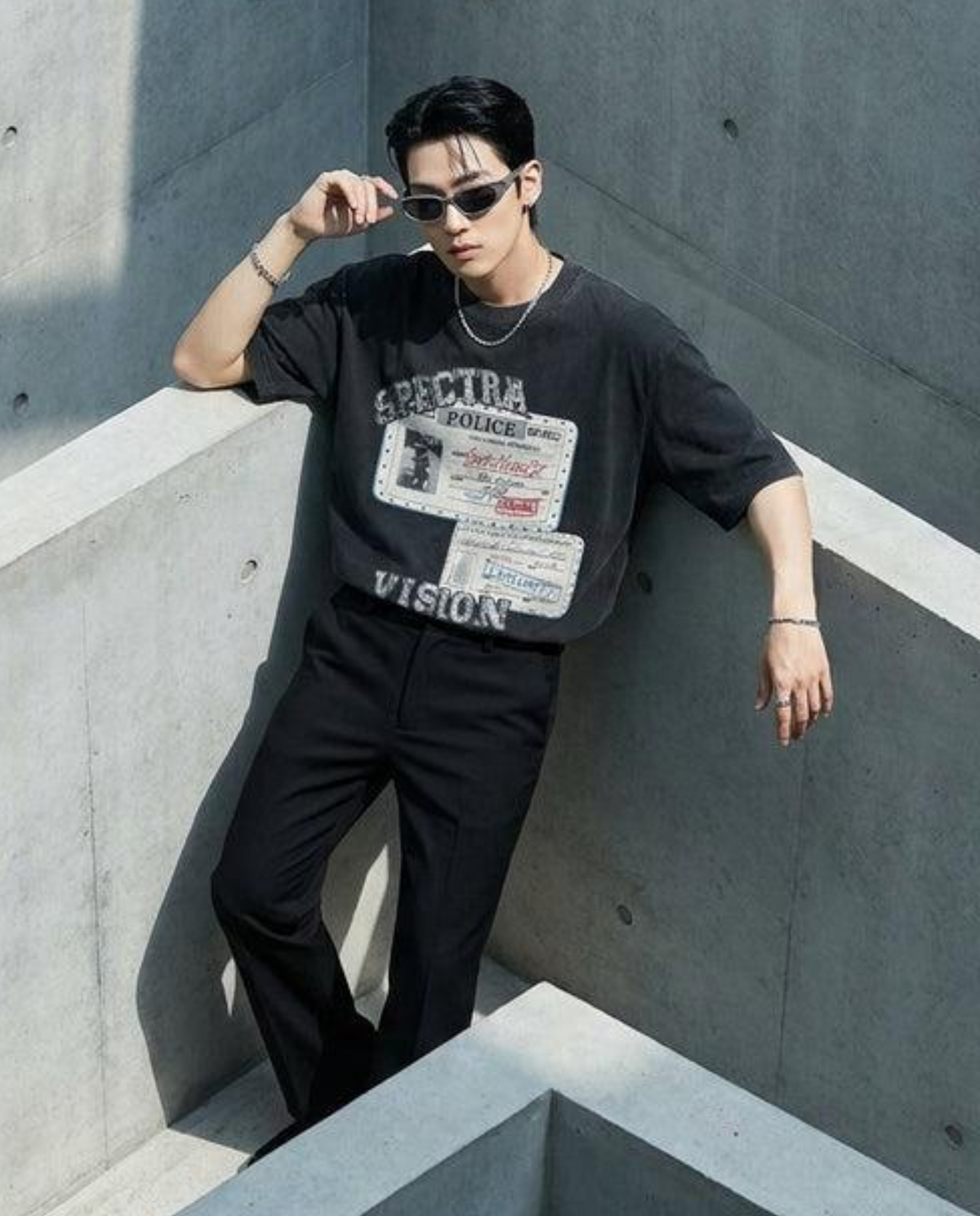 Men’s oversized black graphic T-shirt streetwear outfit paired with black trousers and sunglasses, showcasing a modern casual fashion style.